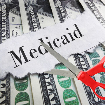 Medicaid newspaper headline on cash with scissors about to cut A Quarter of Americans Are on Medicaid