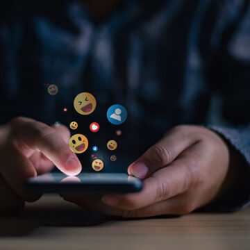 Young man using smartphone sending emojis, diverse positive emoji coming out of mobile phone. Mobile application for chatting, creative image, Social media concept. Welcome to the Poastocracy