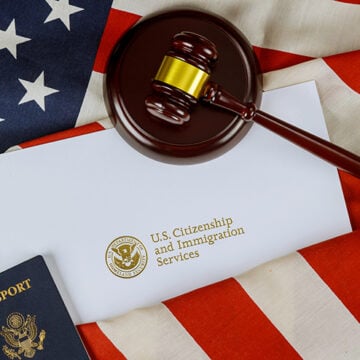 Wooden gavel justice law with Official department U.S deportation USCIS Department of Citizenship Immigration Security United States on American flag If You Cheated to Become American, You Were Never American