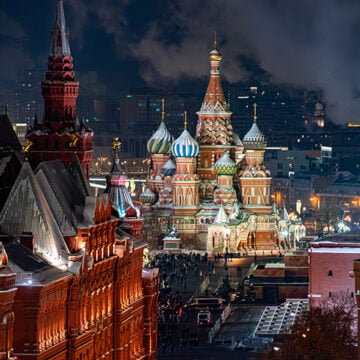 Top view of St. Basil's Cathedral in Moscow at night, with its vibrant domes illuminated, surrounded by historic buildings and the Kremlin towers under a cold winter sky, Russia Russia Diminished?