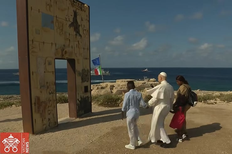 POPE_Lampedusa Caption: Pope Leo XIV walks hand-in-hand with African migrants through the "Gateway to Europe" monument on July 4, 2026, on the Italian island of Lampedusa. (Vatican News / Vatican Dicastery for Communication)